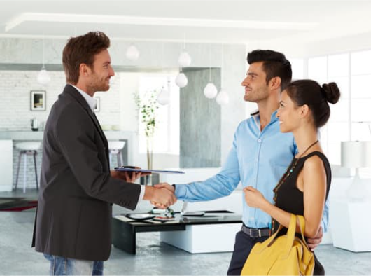couple shaking hands with a letting agent in a home